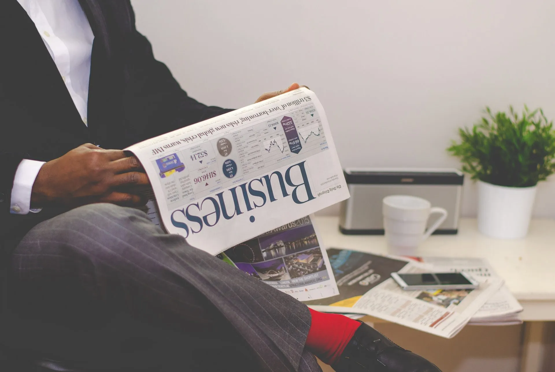 坐在辦公桌前讀財經報紙的人，只看得到手和報紙